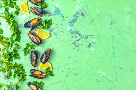 Seafood mussels with lemon and parsley on green concrete table surface, top view, copy space for you text