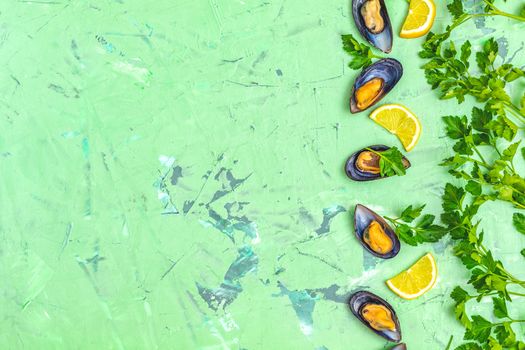 Seafood mussels with lemon and parsley on green concrete table surface, top view, copy space for you text