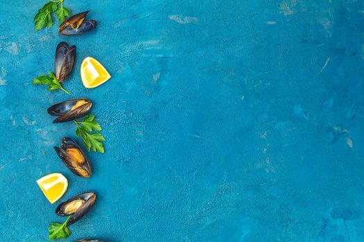 Seafood mussels with lemon and parsley on dark blue concrete table surface, top view, copy space for you text. Food background