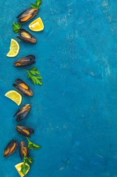 Seafood mussels with lemon and parsley on dark blue concrete table surface, top view, copy space for you text