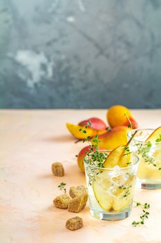 Cold pear white tea with thyme on the pink concrete table background. Festive summer drinks, pear thyme cocktail. Selective focus, space for text