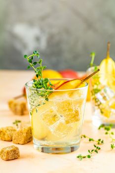 Cold pear white tea with thyme on the wooden background. Festive summer drinks, pear thyme cocktail. Selective focus, space for text.