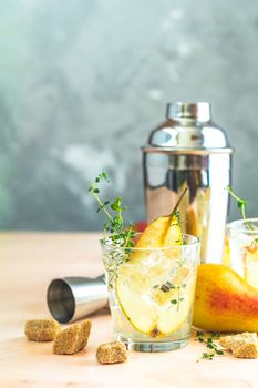 Cold pear white tea with thyme on the wooden background. Festive summer drinks, pear thyme cocktail. Selective focus, space for text