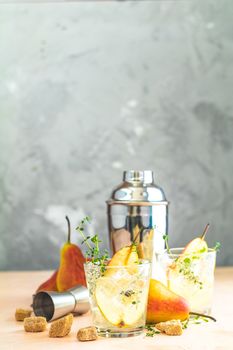 Cold pear white tea with thyme on the pink concrete table background. Festive summer drinks, pear thyme cocktail. Selective focus, space for text