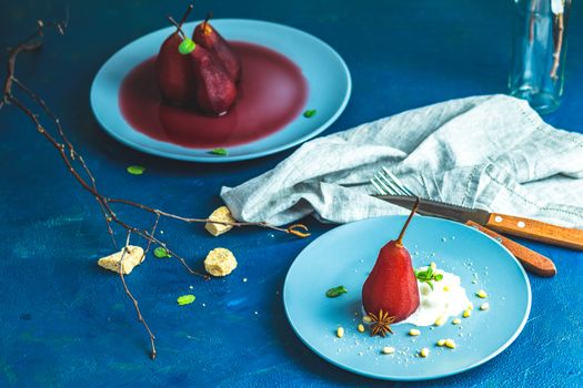 Pears in wine. Traditional dessert pears stewed in red wine with wine sauce on plate on blue concrete surface. Concept for romantic dinner dessert