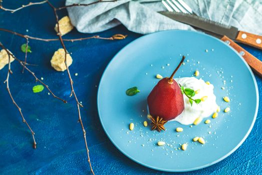 Pears in wine. Traditional dessert pears stewed in red wine with chocolate sauce on plate on blue concrete surface. Concept for romantic dinner dessert. Simple Paleo style dessert pear