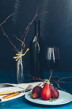 Traditional dessert pears stewed in red wine with chocolate sauce on plate on blue concrete surface. Concept for romantic dinner dessert. Simple Paleo style dessert pear poached in pomegranate juice.