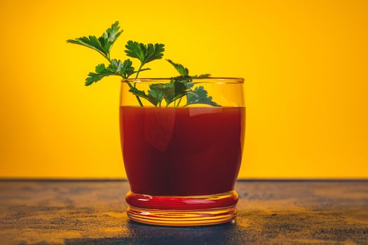 Delicious tomato bloody mary cocktail on dark blue concrete table with spot light. Yellow background.