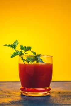 Delicious tomato bloody mary cocktail on dark blue concrete table with spot light. Yellow background.