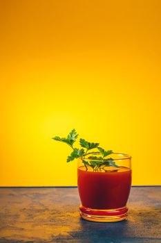 Delicious tomato bloody mary cocktail on dark blue concrete table with spot light. Yellow background.