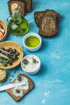 Traditional greek italian appetizer dried black olives with bread and olive oil served on over a blue concrete table surface background