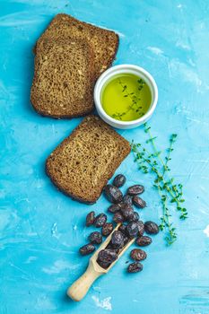 Traditional greek italian appetizer dried black olives with bread and olive oil served on over a blue concrete table surface background