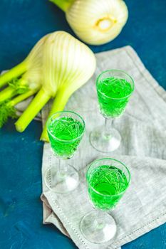 Traditional italian or czech liqueur or bitter with fennel. Three absinthe glass. Dark blue concrete table surface background, copy space for you text.