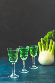 Traditional italian or czech liqueur or bitter with fennel. Three absinthe glass. Dark blue concrete table surface background, copy space for you text.