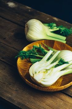 Fresh Florence fennel bulbs or Fennel bulb in plate on wooden background. Healthy and benefits of Florence fennel bulbs