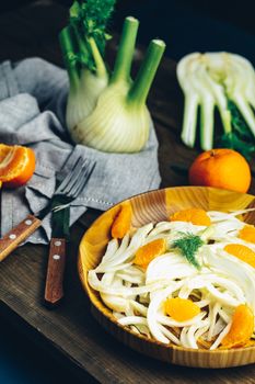 Traditional sicilian italian salad with fennel and tangerine. Fennel and orange citrus salad, on wooden plate. Modern, light, raw, veg cuisine. Winter salad.