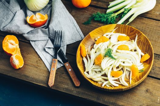 Traditional sicilian italian salad with fennel and tangerine. Fennel and orange citrus salad, on wooden plate. Modern, light, raw, veg cuisine. Winter salad.