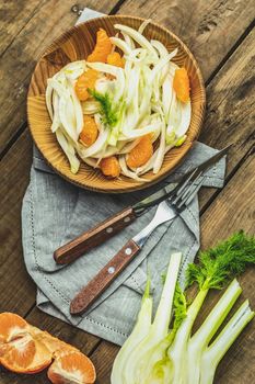 Traditional sicilian italian salad with fennel and tangerine. Fennel and orange citrus salad, on wooden plate. Modern, light, raw, veg cuisine. Winter salad.