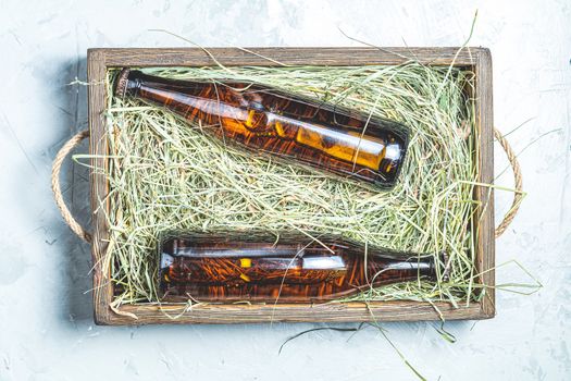 Craft beer with dried grass in wooden box on gray concrete surface background. Top view, flat lay