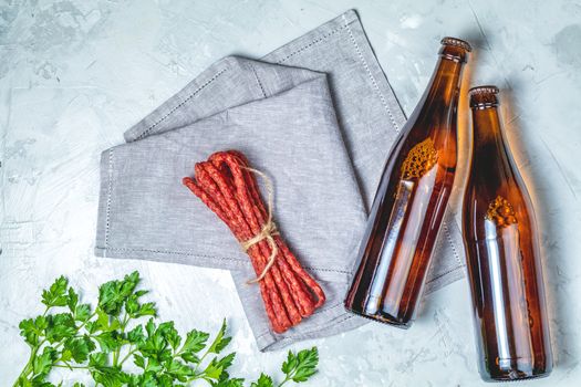 Craft beer with sausages kabanosi and green parslye on gray concrete surface background, copy space for you text, rustic style.