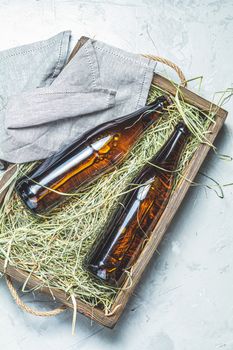 Craft beer with dried grass in wooden box on gray concrete surface background