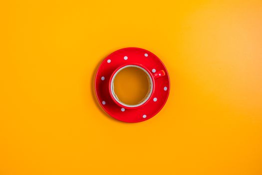 Red in white dotted cup of tea on yellow surface background. Minimalism, top view, copy space for you text.