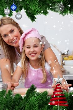 Mother and daughter baking Christmas cookies in the kitchen against snow falling