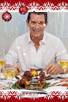 Smiling man eating turkey in Christmas dinner against snow falling