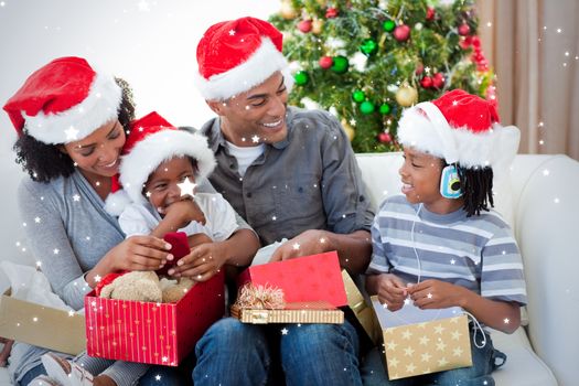 Happy family opening Christmas presents against snow