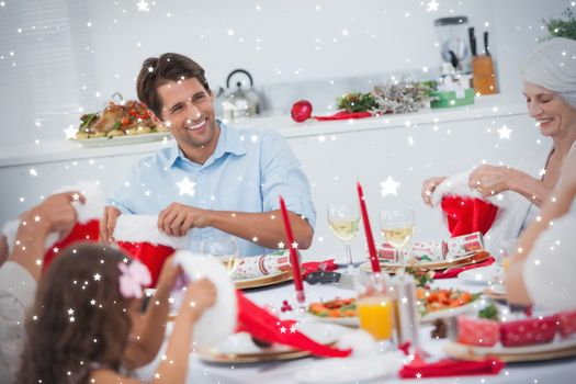 Composite image of Cheerful family dining together against snow