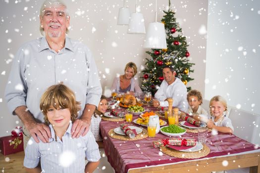 Composite image of Grandfather and grandson standing beside the dinner table against snow falling