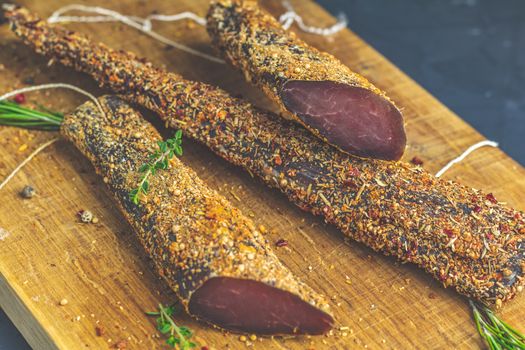 Jerky, basturma, dried meat beef, meat smoked jerky with spices on wooden cutting board, close up.