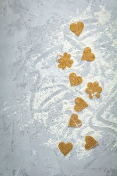 Raw homemade uncooked ginger cookies over light gray concrete surface. View from above, copy space for text, beautiful valentine day sweet food cooking card.