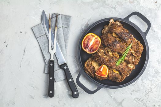 Delicious baked roast pork meat in black frying pan with garlic,  and spices. Dish for dinner. Top view, flat lay, copy space for you text