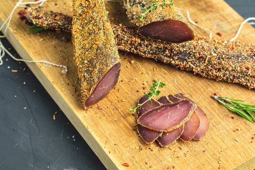 Jerky, basturma, dried meat beef, meat smoked jerky with spices on wooden cutting board, close up.