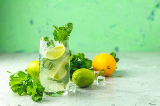 Mojito cocktail with lime and mint in highball glass on a gray and green concrete stone surface background. With copy space for your text