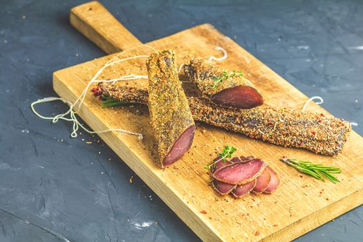 Jerky, basturma, dried meat beef, meat smoked jerky with spices on wooden cutting board, close up.