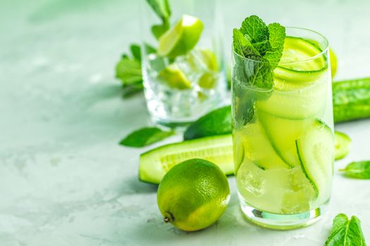 Detox cocktail of mint, cucumber and lemon and mojito cocktail with lime and mint in highball glasses on a gray concrete stone surface background. With copy space for your text