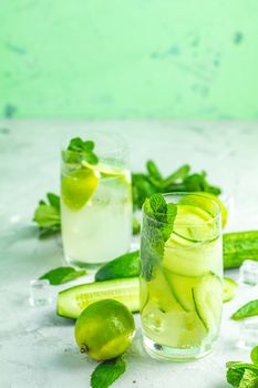 Detox cocktail of mint, cucumber and lemon and mojito cocktail with lime and mint in highball glasses on a gray concrete stone surface background. With copy space for your text