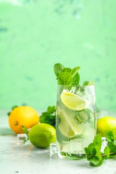 Mojito cocktail with lime and mint in highball glass on a gray and green concrete stone surface background. With copy space for your text