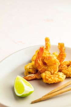 Fried Shrimps tempura in light plate on pink or peach concrete surface background. Copy space for you text. Seafood tempura dish of traditional asian cuisine.