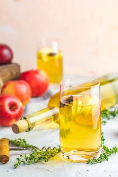 Bottle and glasses of homemade organic apple cider with fresh apples in box, light concrete table surface. Shallow depth of the field.