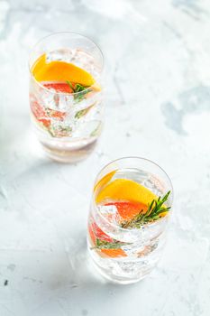 Alcoholic cocktail with grapefruit, soda, ice, gin and rosemary, light gray concrete table background, selective focus, shallow depth of the field.