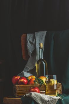 Apple cider vinegar or fruits tea with apple slices in glass with ripe red apples in box, dark vintage rustic style. Shallow depth of the field.