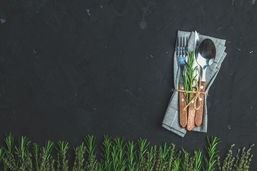 Rustic vintage set of cutlery knife, spoon, fork. Black stone concrete surface background. Top view, copy space.