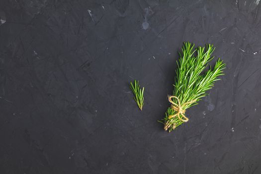 Rosemary bunch of bouquets on black stone concrete textured surface background. Top view with copy space for your text.