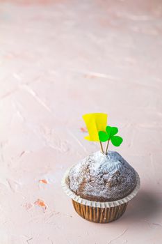 Tasty delicious homemade muffin on light pink living coral stone concrete surface with knitting hearts, copy space. Sweet food for Saint Patrick day.