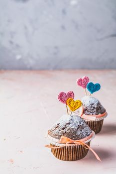 Tasty delicious homemade muffin on light pink living coral stone concrete surface with knitting hearts, copy space. Sweet food, Beautiful food concept for Valentine day or Wedding, Birthday