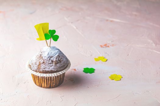 Tasty delicious homemade muffin on light pink living coral stone concrete surface with knitting hearts, copy space. Sweet food for Saint Patrick day.