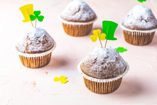 Tasty delicious homemade muffin on light pink living coral stone concrete surface with knitting hearts, copy space. Sweet food for Saint Patrick day.